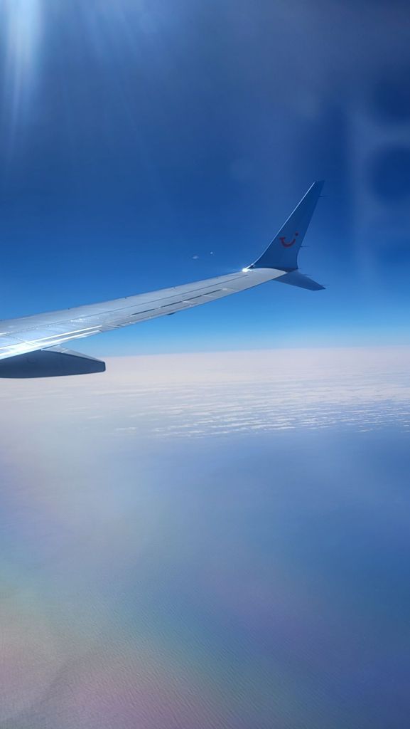 Photo of the ocean and the wing of an aeroplane.